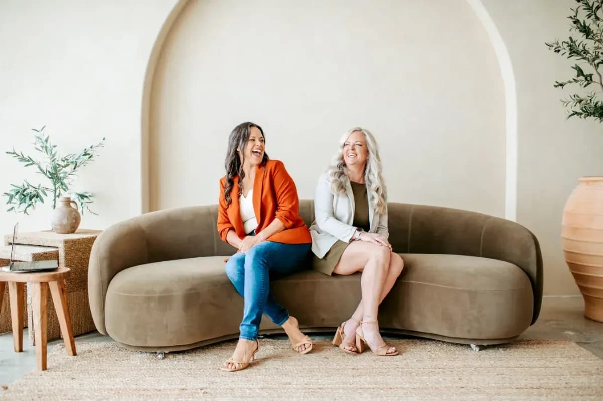 Staci and Steffanee laughing together on a couch